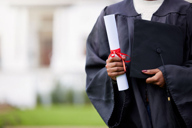 Midsection of man holding mortarboard