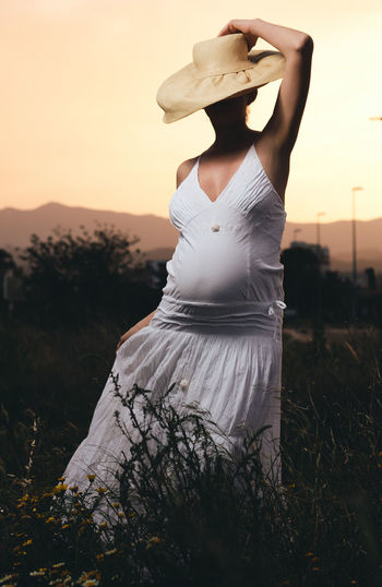 Pregnant woman standing on field against sky