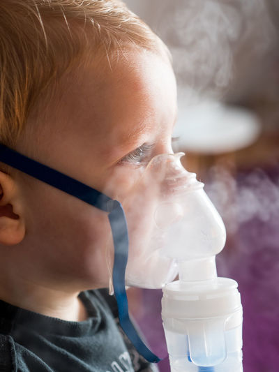 Close-up of cute baby boy taking steam at home