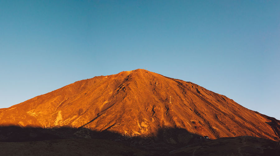 Scenic view of volcanic mountain against clear sky at sunrise 