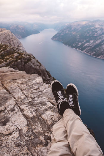 Person cross legged at edge of cliff with a fjords view in norway