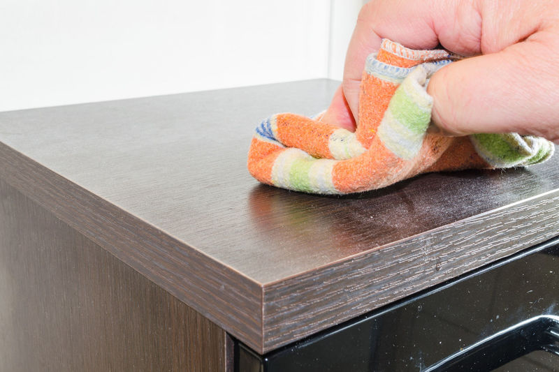 Cropped hand cleaning wooden table with duster