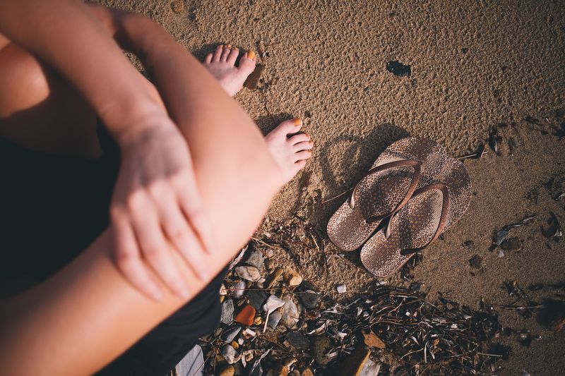 Low section of woman sitting on sand at beach