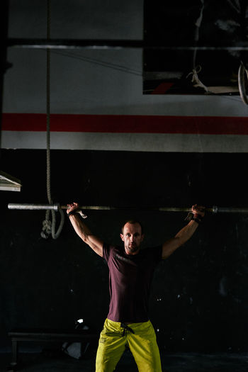 Fit young man training with a bar in a garage gym