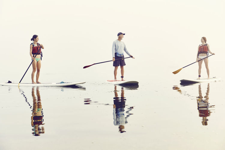 A group of friends standup paddle boarding on an early foggy morning