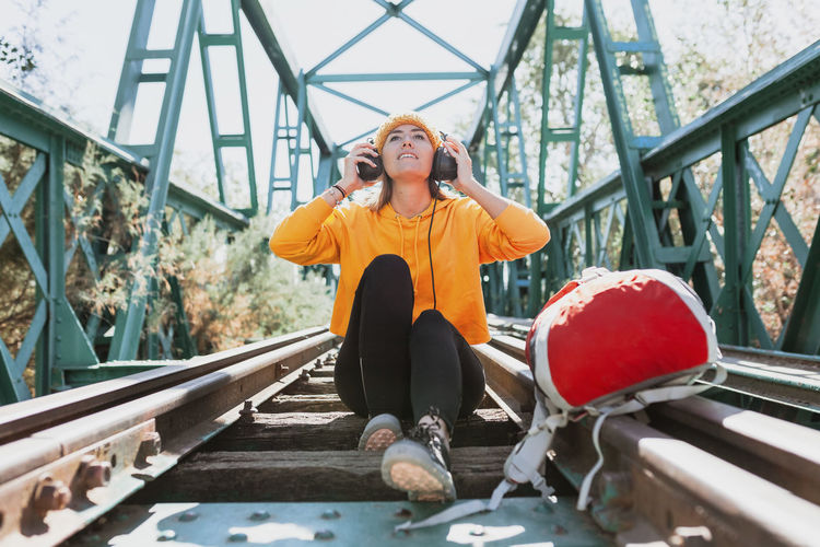 Full length of woman sitting on railway bridge