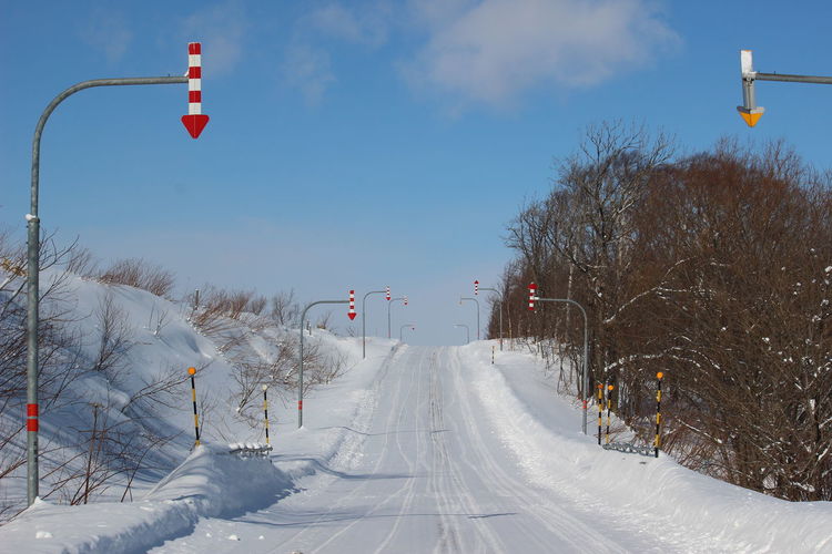 Road amidst snow covered land against sky
