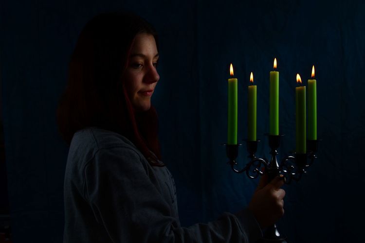 Close-up of girl holding candle in the dark