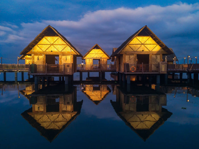 Wooden houses with reflection by laguna lake against sky