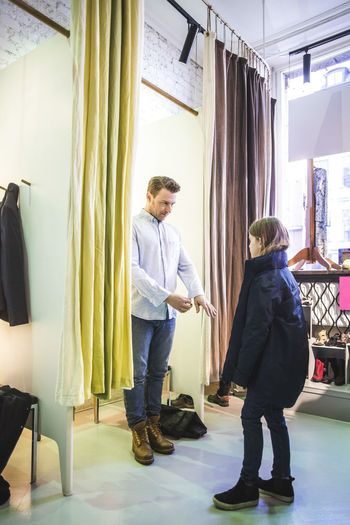 Father trying shirt for daughter while standing in fitting room at boutique