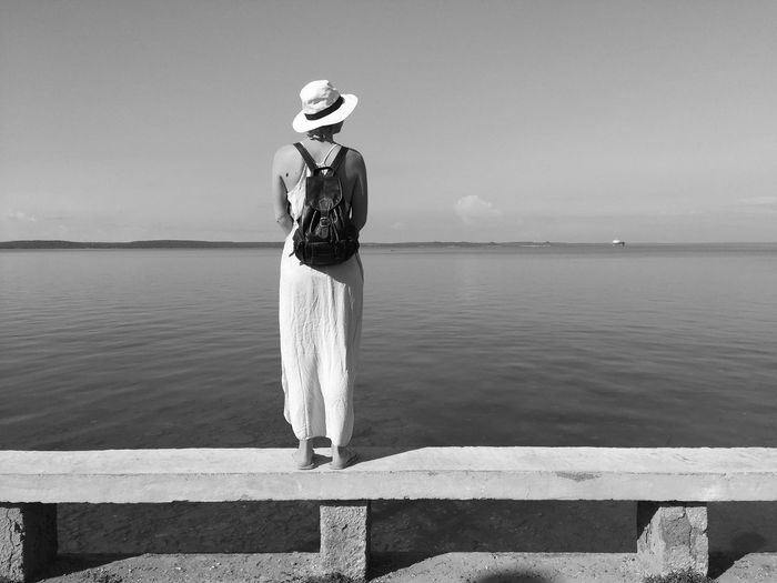 Rear view of woman standing by sea