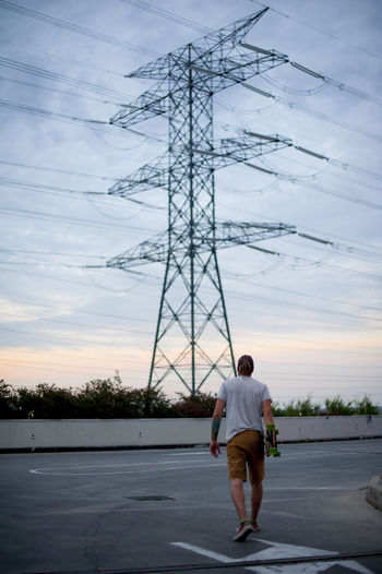 Rear view of man standing on road against sky