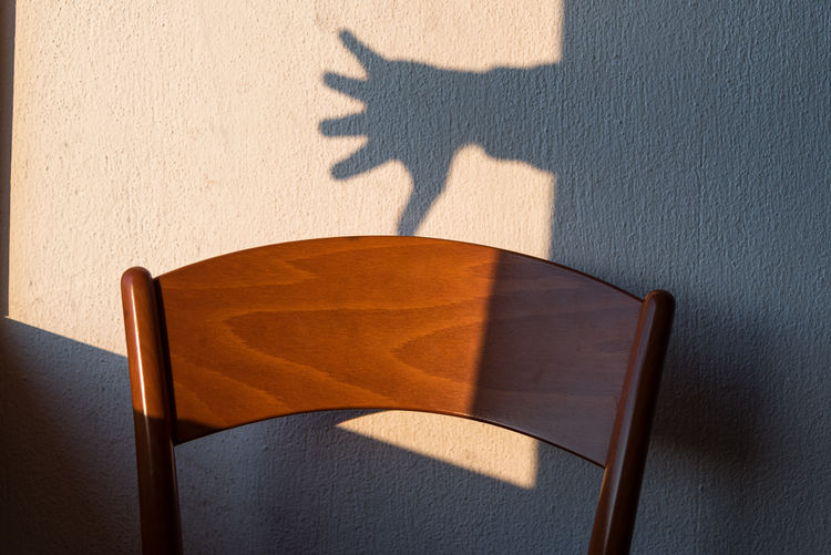 Shadow of person on chair against wall