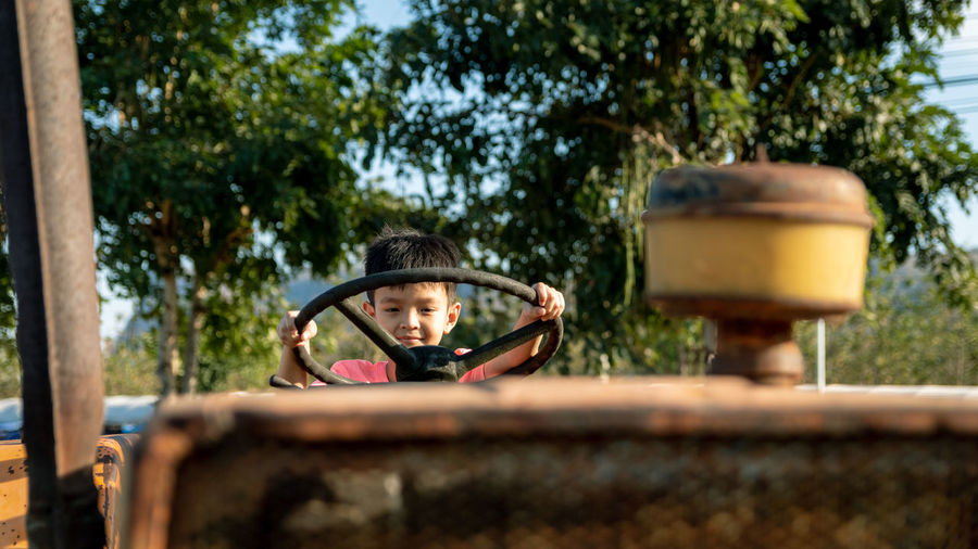 Portrait of cute boy holding steering wheel of land vehicle