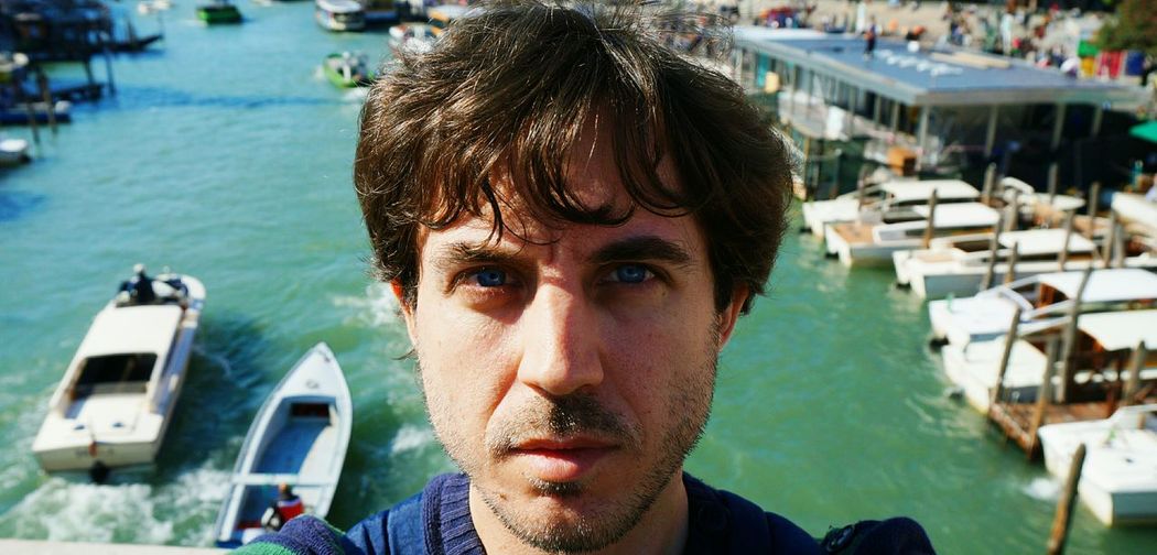 Close-up portrait of young man against canal