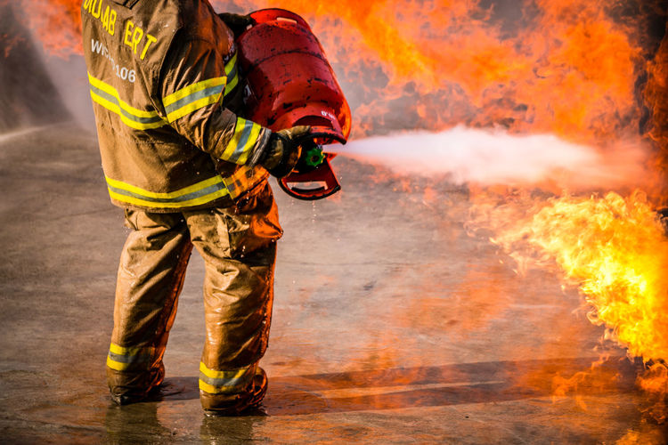 Low section of firefighter spraying extinguisher on fire