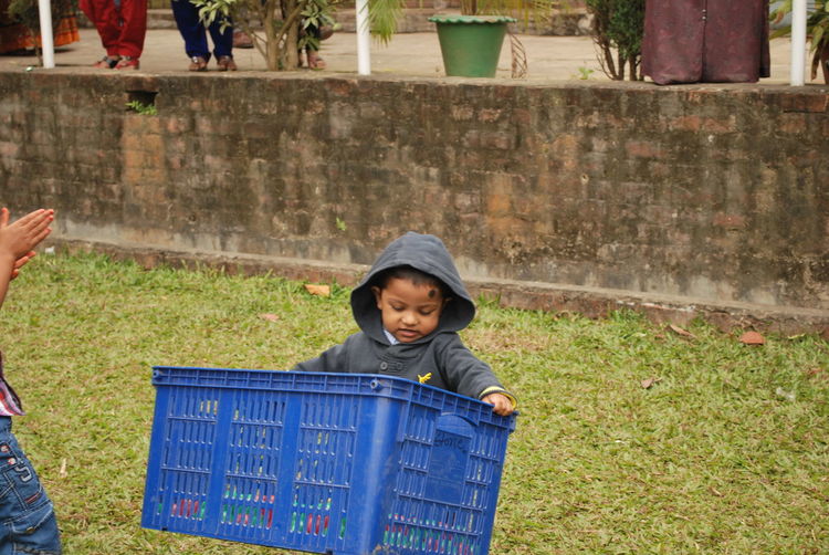High angle view of boy carrying plastic crate on field
