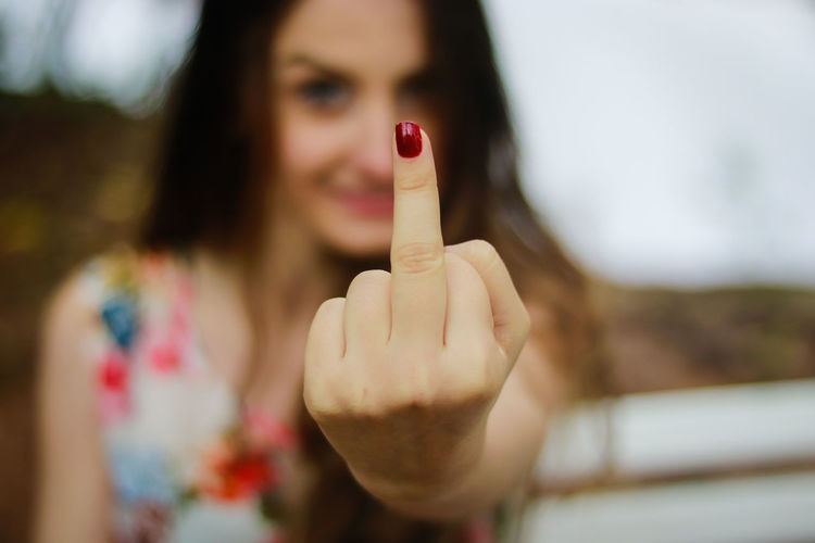 Portrait of young woman showing middle finger