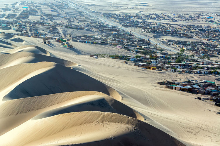 High angle view of sand dunes in desert with huacachina village in background