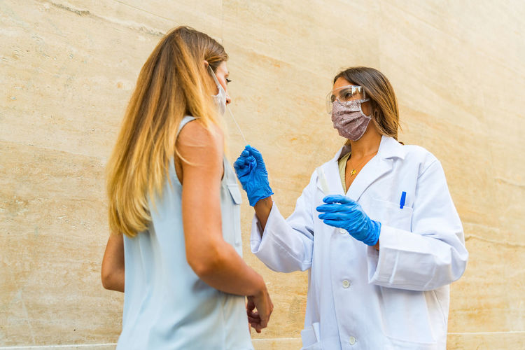 Doctor wearing mask examining woman outdoors
