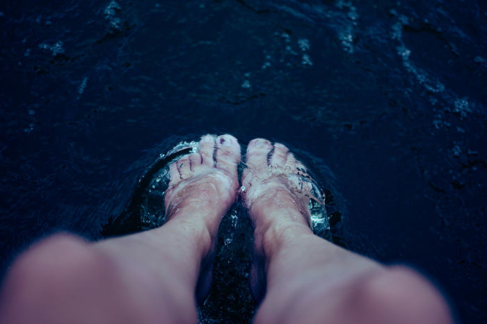LOW SECTION OF PERSON FEET IN SEA