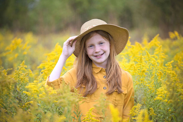 Portrait of smiling girl with yellow flowers on field