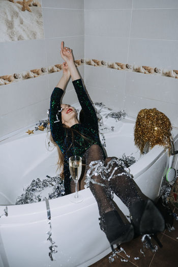 New years party birthday celebration. happy young woman in evening dress sitting in the bathtub