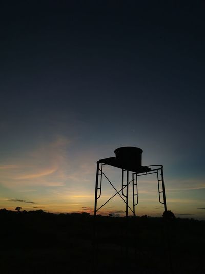 Silhouette water tower against sky during sunset