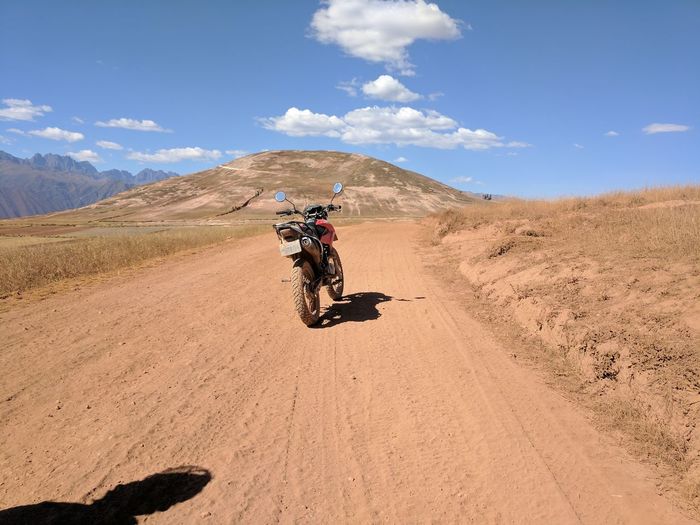 Motorcycle on dirt road against sky