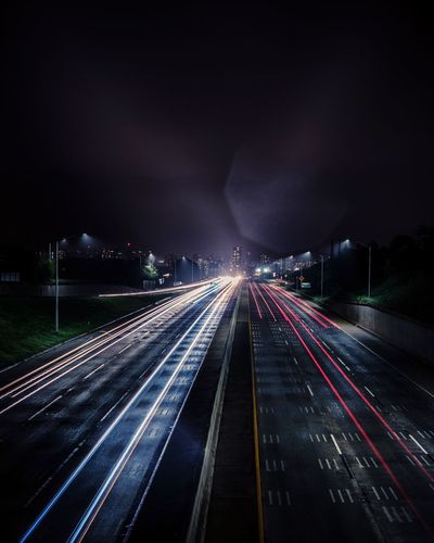 Light trails on road against sky at night