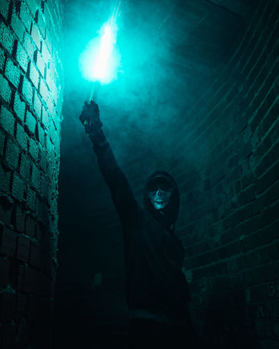 Man holding blowtorch by wall at night