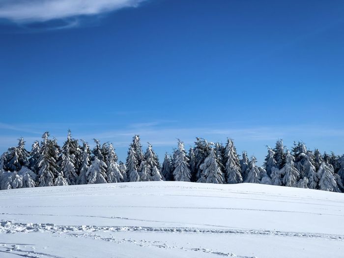 Panoramic view of snow covered landscape against blue sky