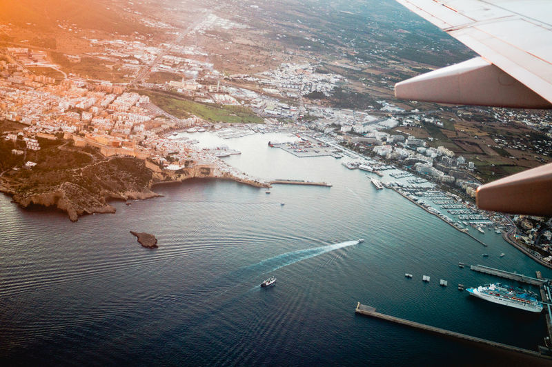 Cropped image of aircraft wing over sea and city