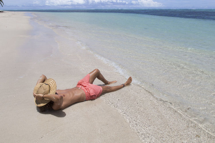Midsection of woman lying on sand at beach