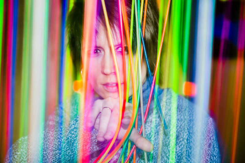 A girl pointing at you in neon colorful strings