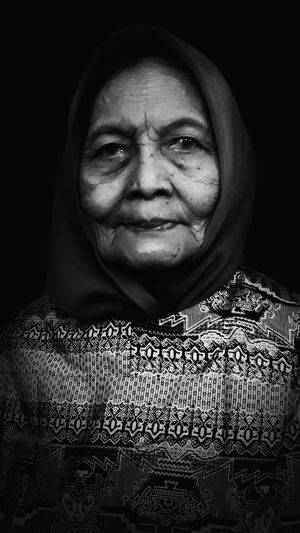 Close-up portrait of smiling woman against black background