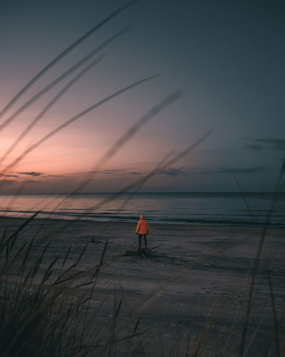 Silhouette man standing on beach against sky during sunset