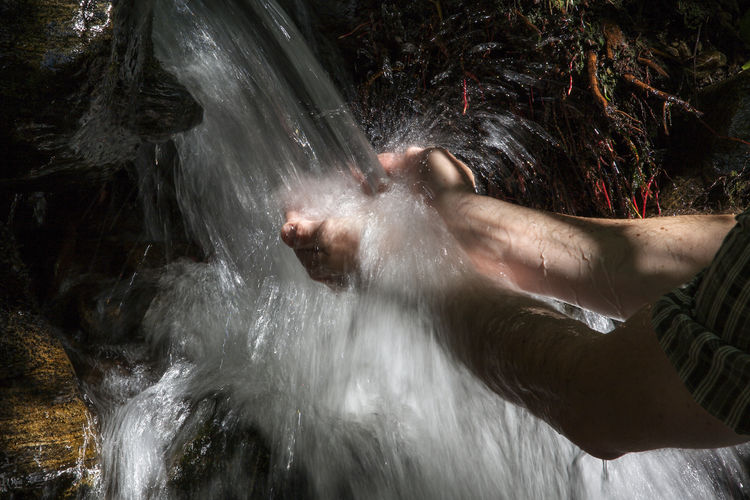Midsection of woman in water at waterfall
