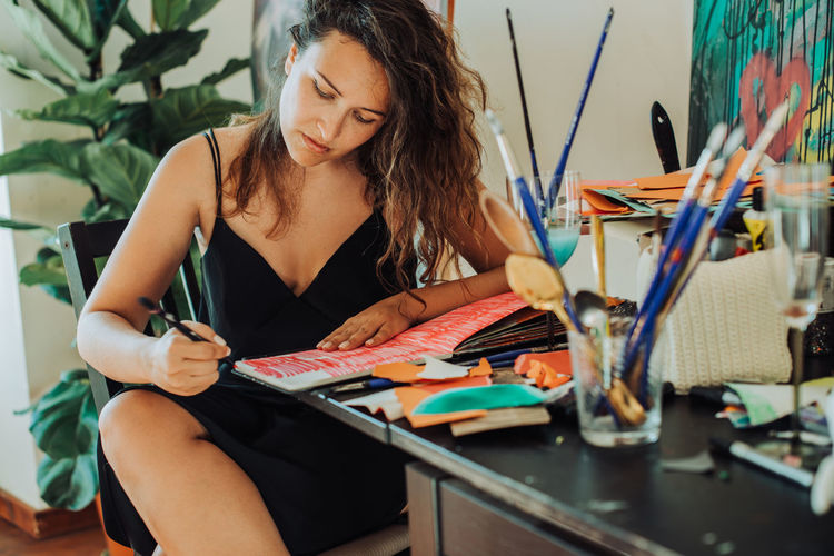 Woman painter focused on work sitting at table in her studio