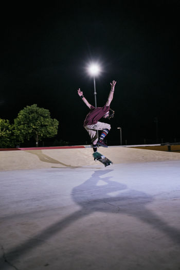 Man skateboarding on street at night