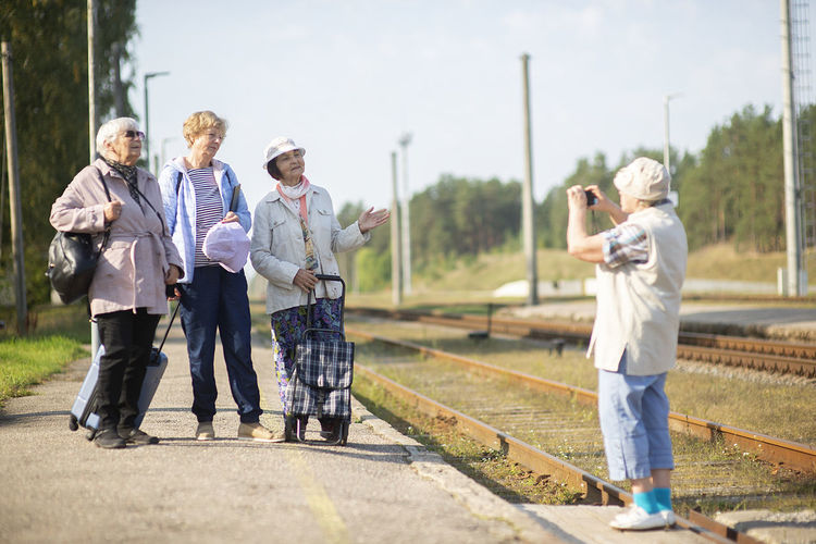 Smiling senior women take a photo on a platform waiting for a train during a covid-19 pandemic
