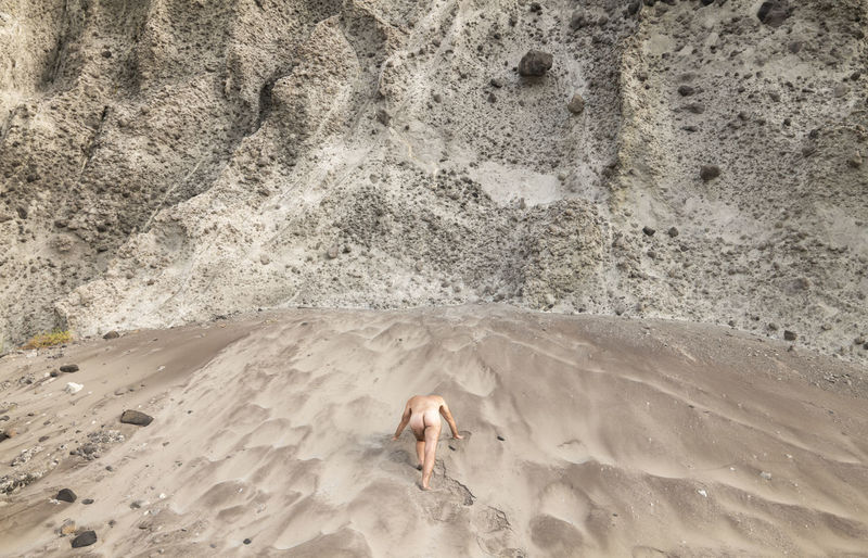 High angle view of shirtless adult man on beach against rock