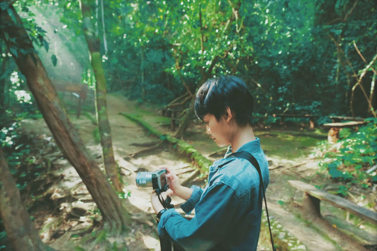 Side view of man photographing in forest
