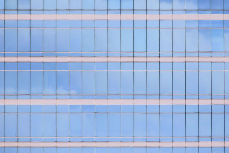 Modern office building elevation. glass curtain wall repeating pattern reflecting cloud.