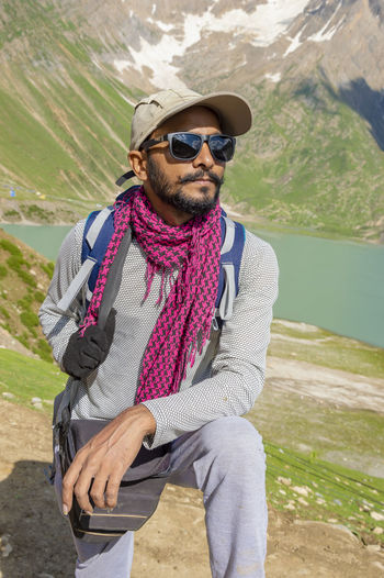 Young man wearing sunglasses standing against mountain