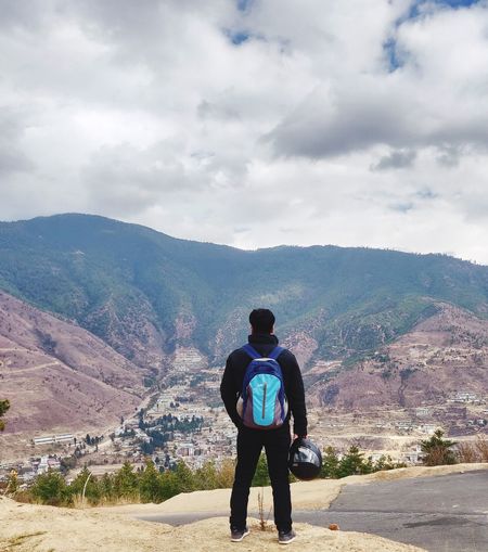 Rear view of man standing on mountain against sky