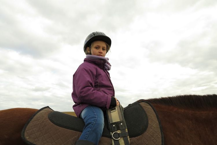 Low angle view of girl riding horse