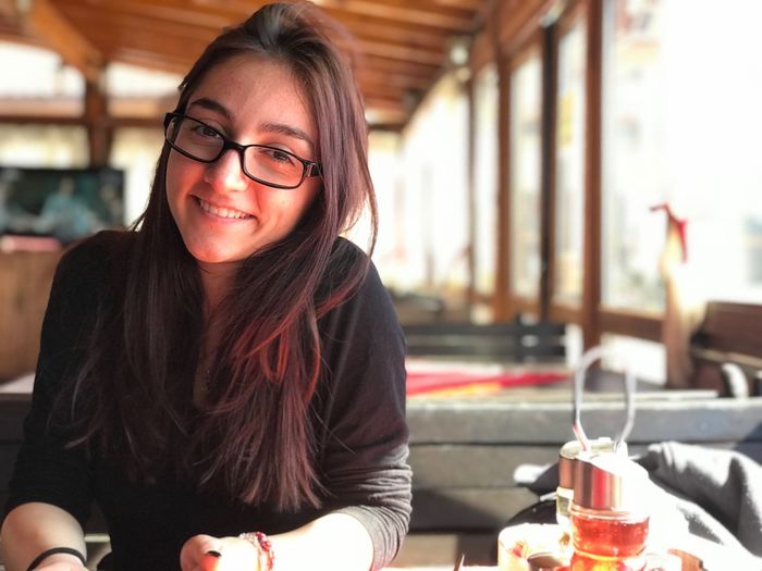 Portrait of smiling young woman wearing eyeglasses sitting at restaurant