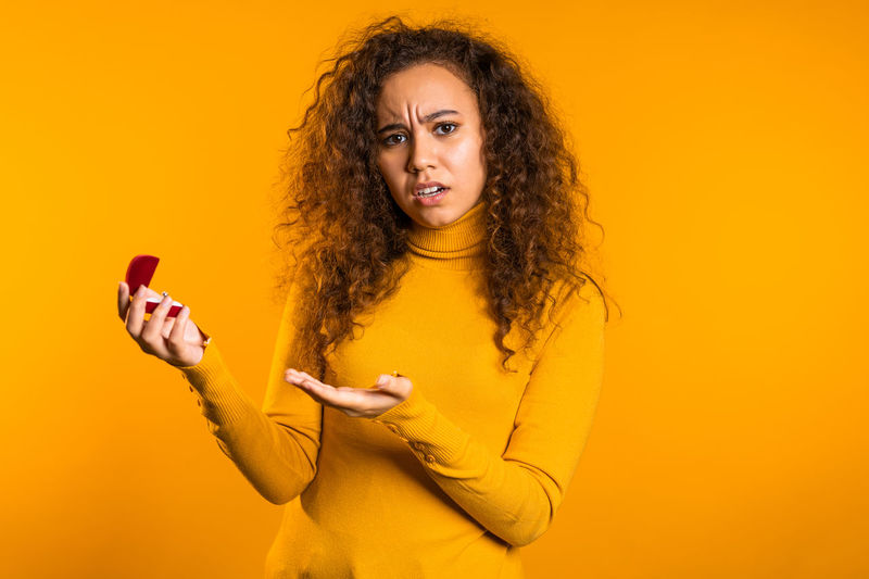 Young woman using mobile phone against yellow background