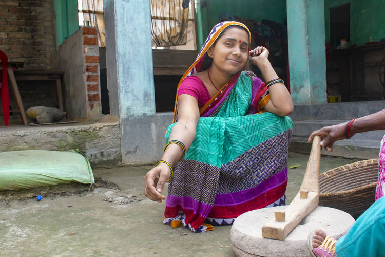Full length of smiling woman wearing sari sitting outdoors